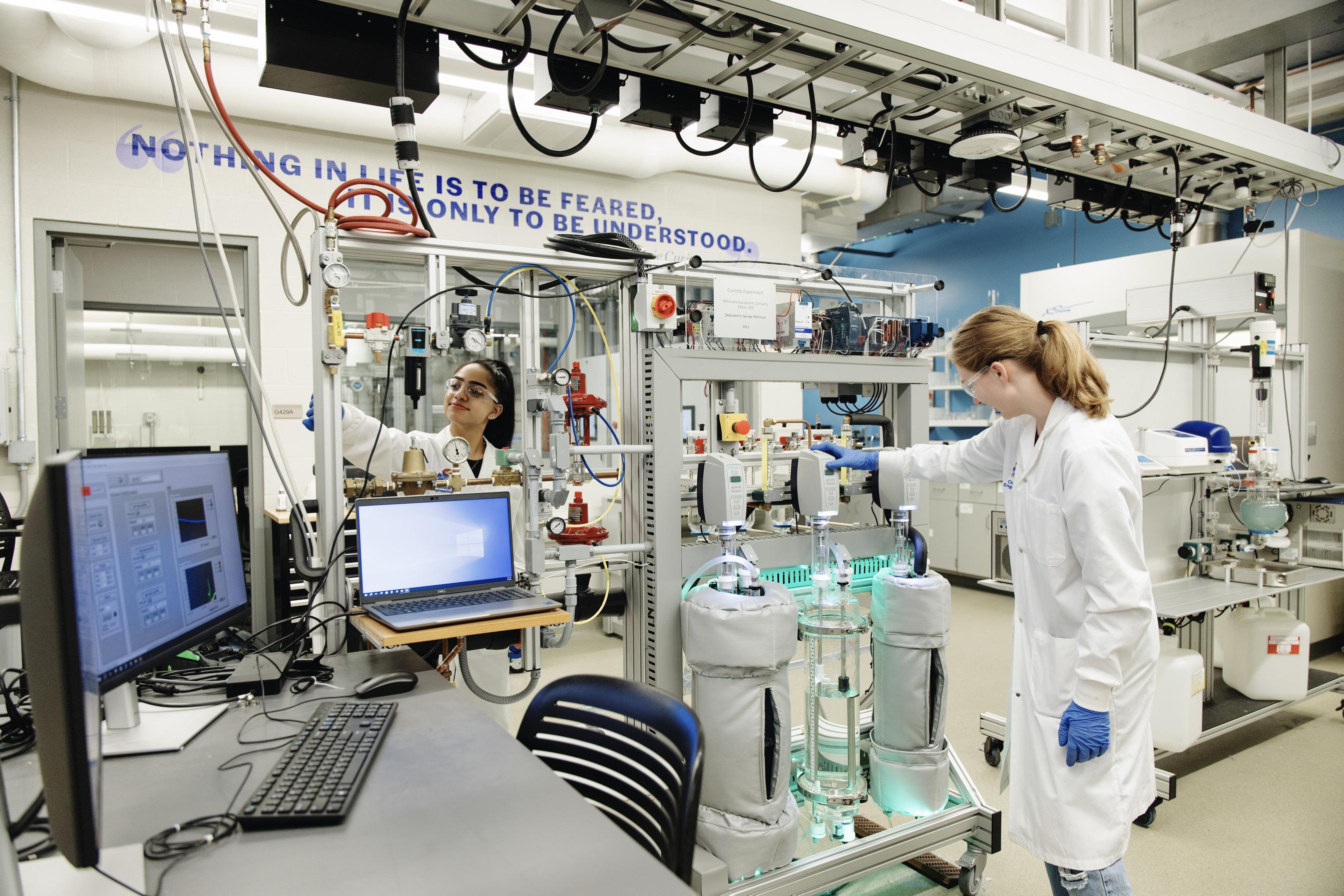 Two students working on opposite sides of the process control machinery